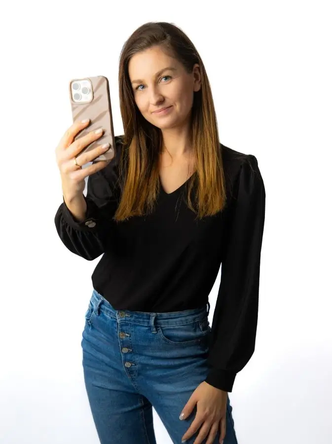 Marta Molik video content creator oraz wedding content creator z telefonem w ręce, patrząca z uśmiechem przed siebie.