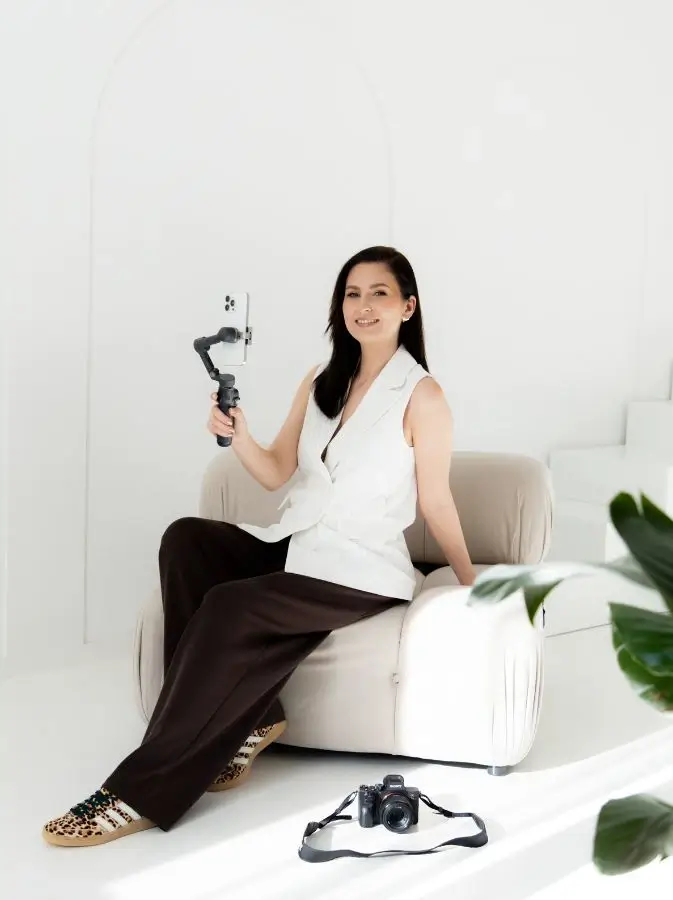 Marta Molik siedząca na kanapie z gimbalem i telefonem w ręku